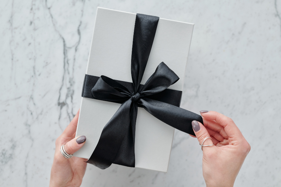 white gift box with black ribbon bow on marble backdrop